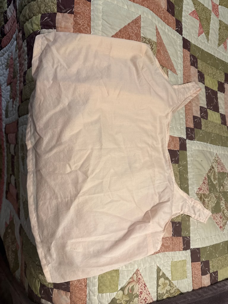 pink tank top sitting on a green, purple, pink and white quilt
