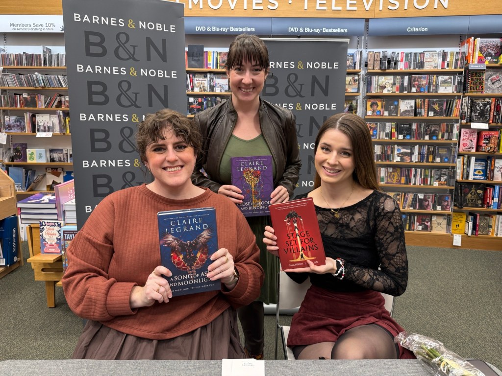 Claire and Shannon holding up their books with Kaite standing behind them holding up and edition of A Rose of Blood and Binding